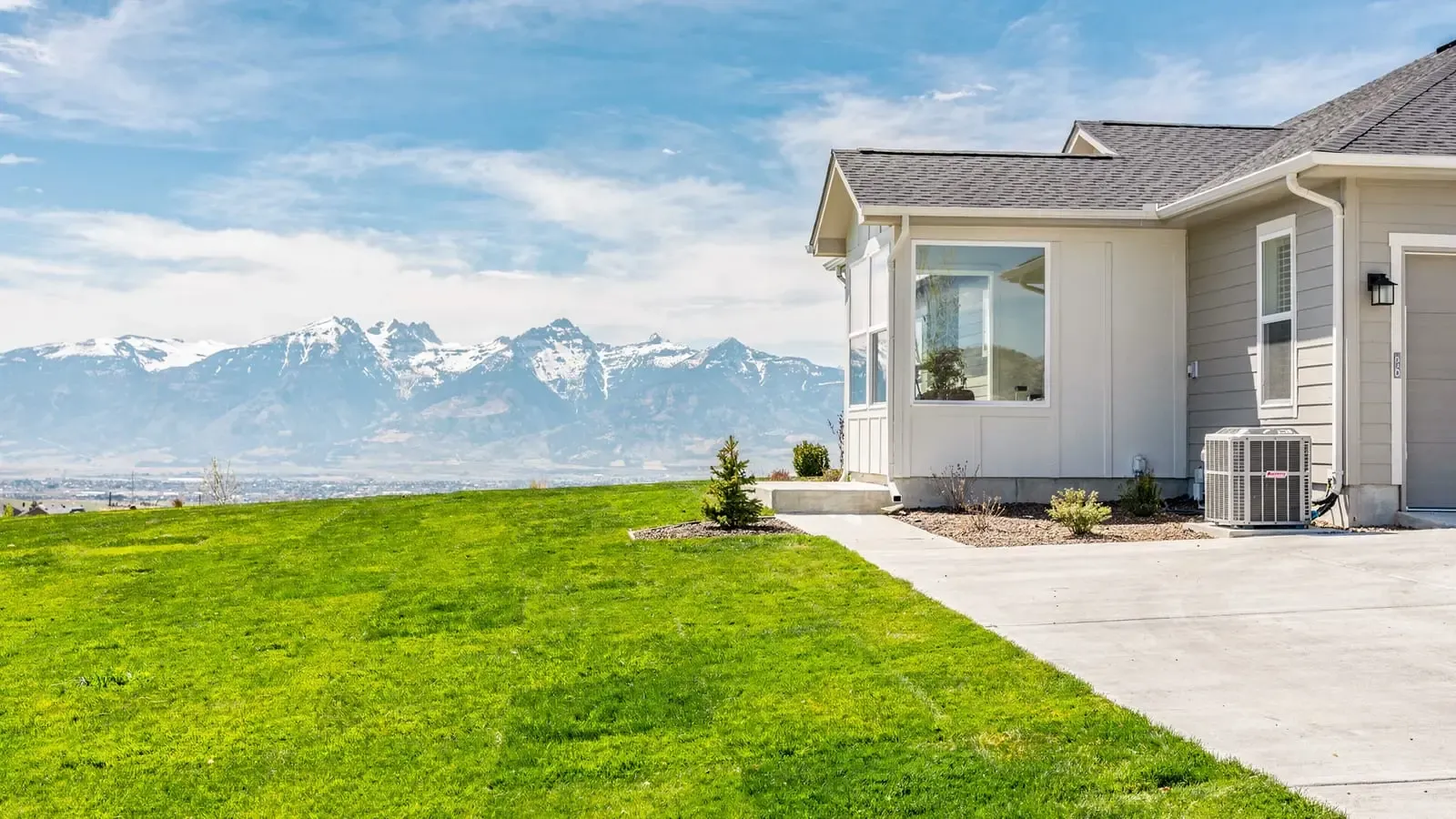 A Front Range home in Littleton with the snow-capped Rockies behind it and a residential AC unit alongside